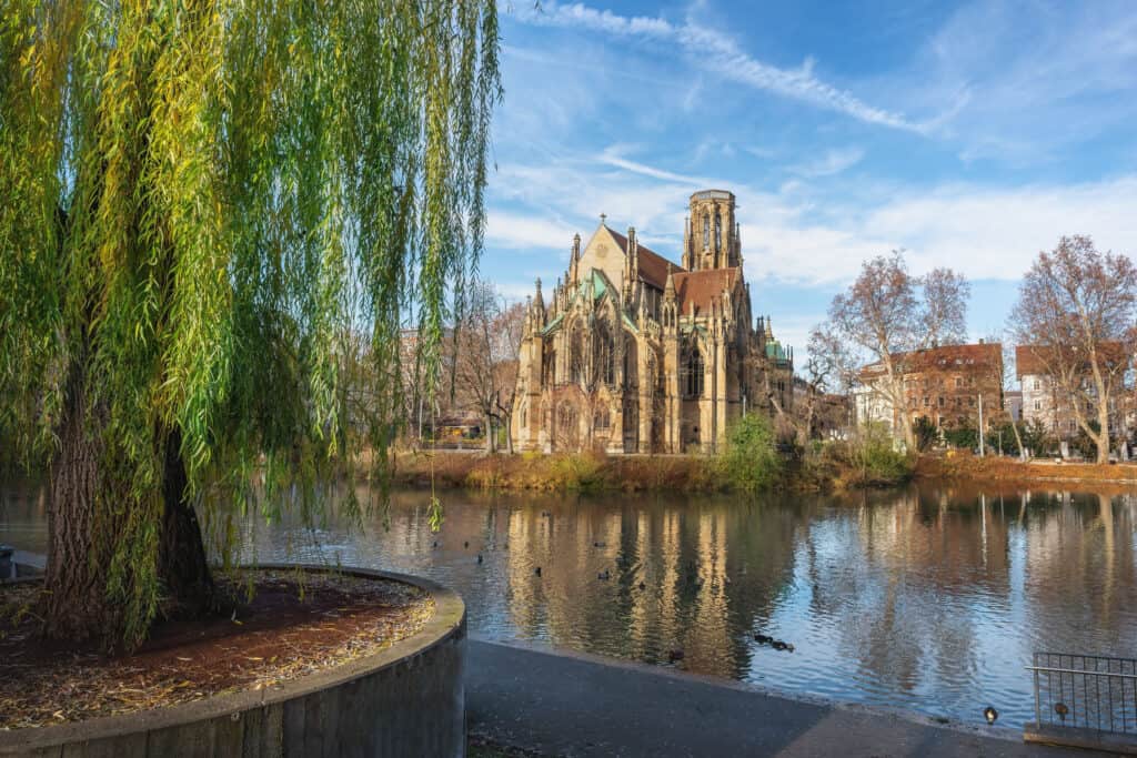Johanneskirche in Stuttgart, a neo-Gothic church reflecting on the Feuersee lake.