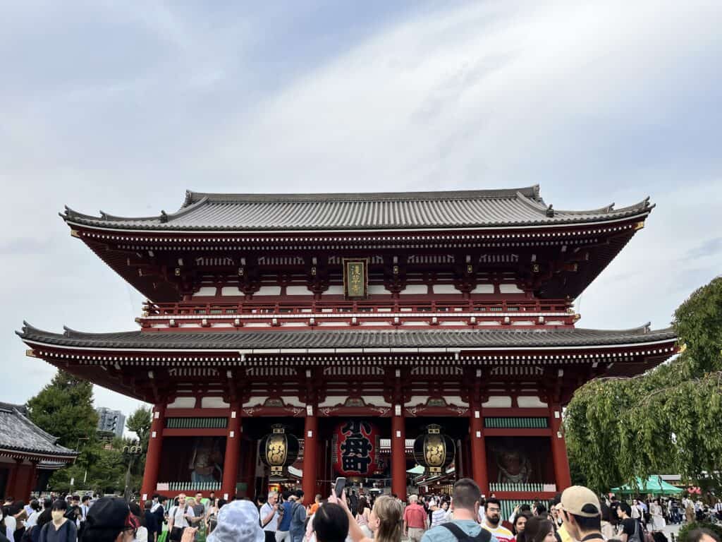 The ornate Main Hall of Senso-ji Temple, with intricate carvings and gold accents under a blue sky in Tokyo, Japan.