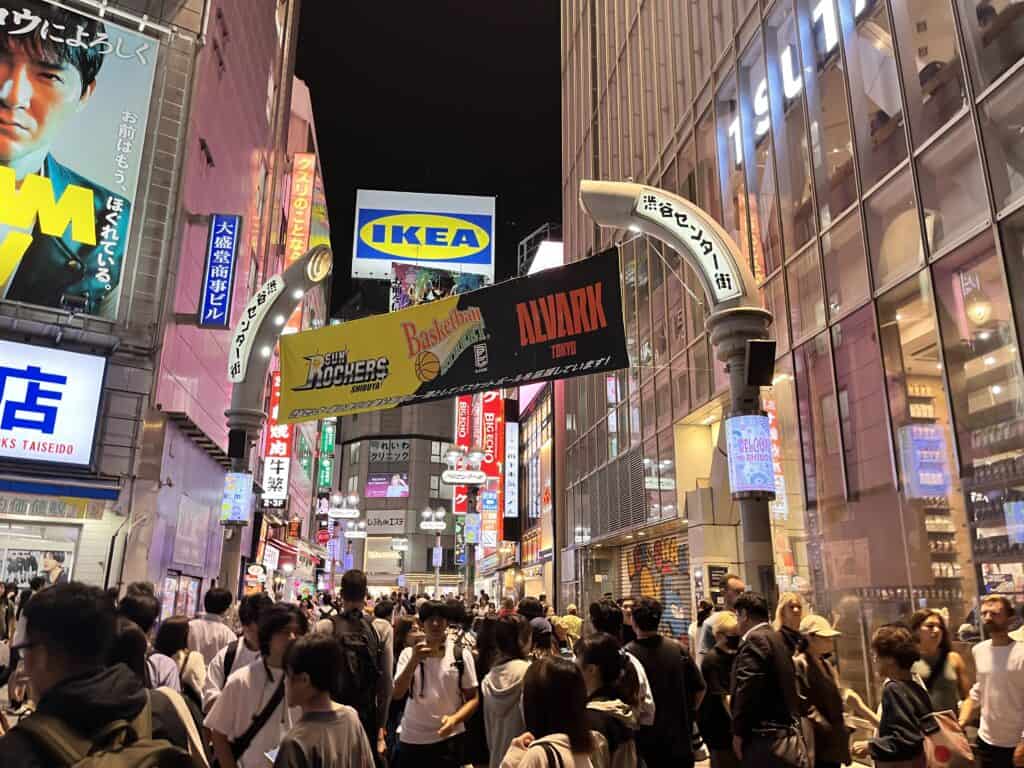 Candid scene of locals and tourists enjoying Shibuya's bustling nightlife with trendy bars and clubs aglow in Tokyo, Japan.