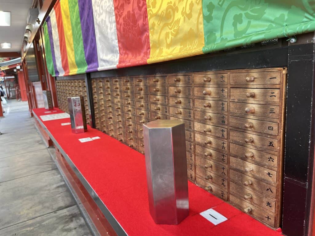 Vibrant omikuji stalls offering traditional Japanese fortune slips to visitors at a bustling Tokyo shrine.