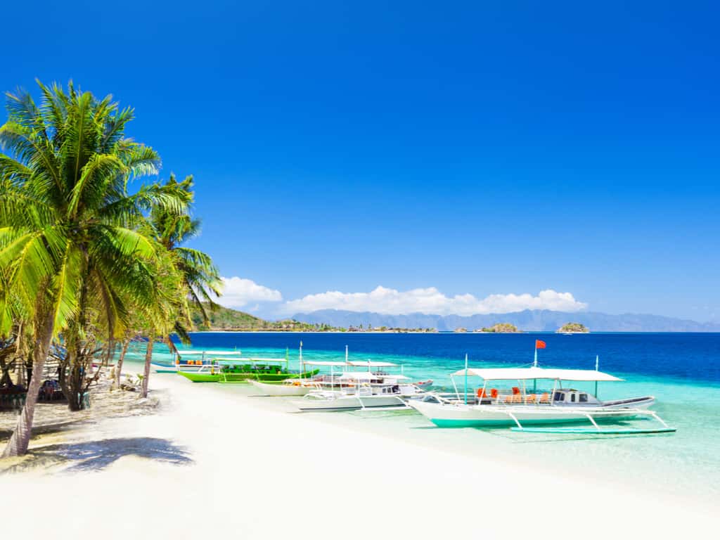 Traditional Filipino outrigger boats, known as 'bangkas,' lined up along Boracay's beach.