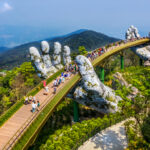 Tourists walking along the Golden Bridge, enjoying panoramic views of the surrounding mountains.