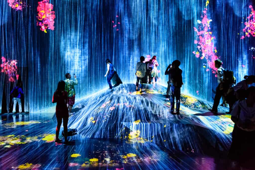  A serene scene showing the 'Water Particles on the Waterfall' installation, with water cascading down in beautifully illuminated patterns.