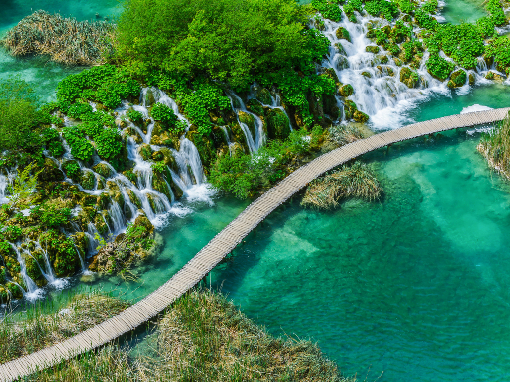 Panoramic view of the cascading waterfalls at Plitvice Lakes National Park, showcasing the park's lush greenery and pristine waters