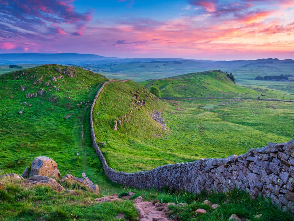 The ancient stones of Hadrian's Wall standing resiliently against a dramatic sky in the British landscape.