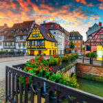 Colorful half-timbered houses lining the canals of Colmar, reflecting in the water.