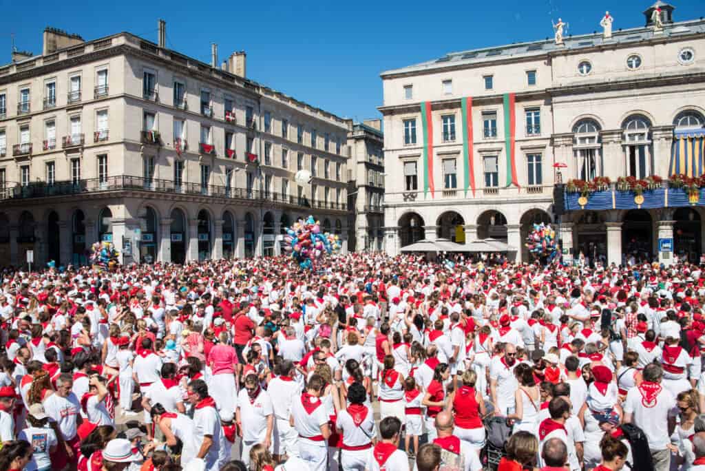Crowds dressed in traditional white and red celebrating the Summer Festival in Bayonne, France.