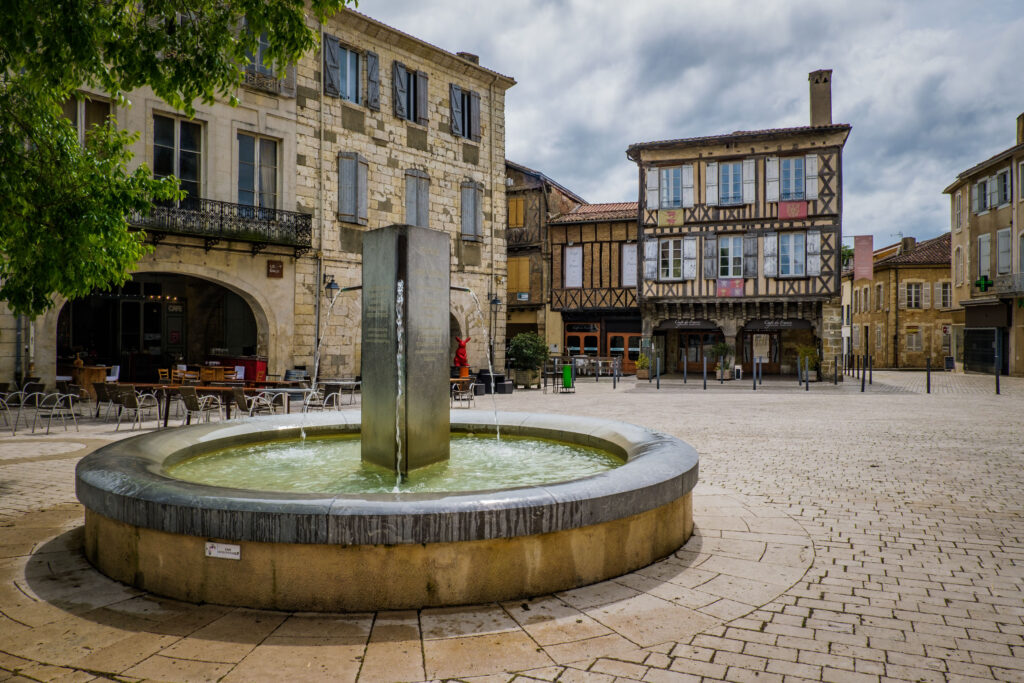 The cobblestone main square of Éauze, France, on May 22, 2021, showcasing medieval buildings and ivy-covered facades.
