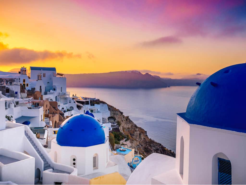 Sunset over Oia, Santorini, casting a warm golden hue over the village and sea.