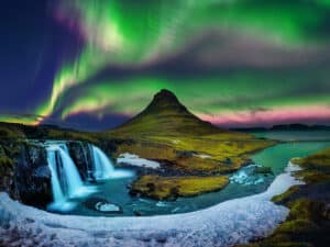 Vivid green and purple hues of the Northern Lights above the distinct shape of Kirkjufell.