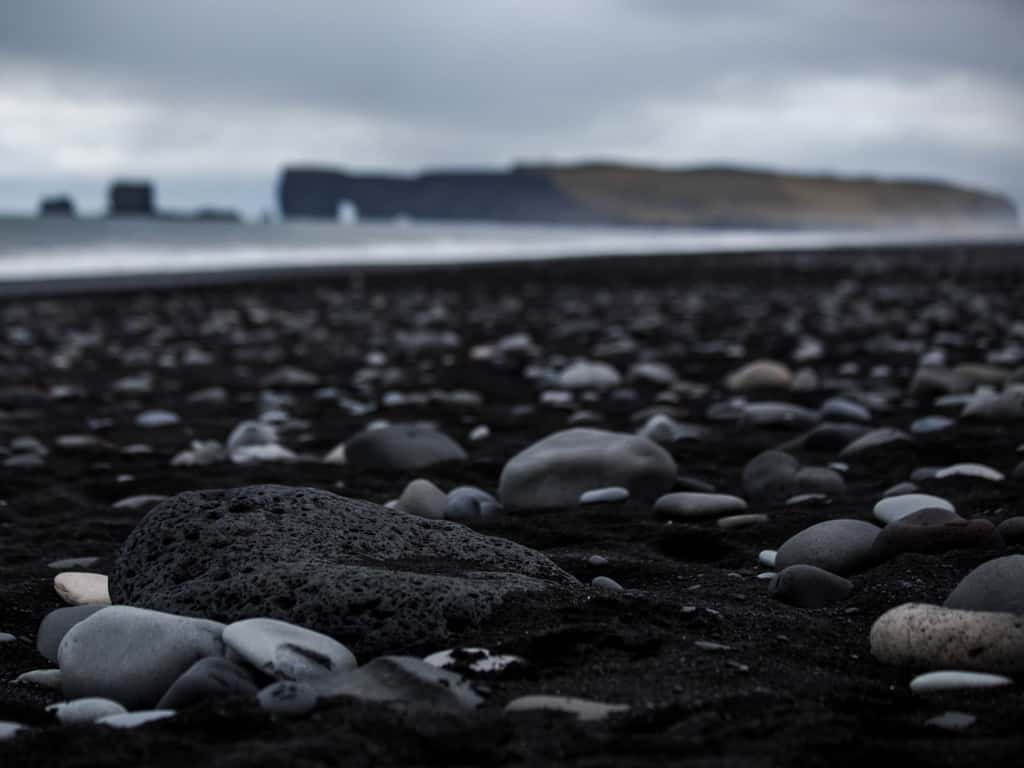 The rugged coastline and natural arches near Vik's Black Beach, highlighting Iceland's dramatic coastal scenery