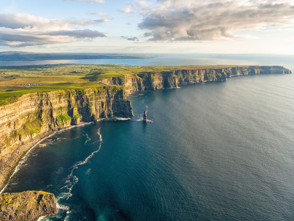 Aerial view of the Cliffs of Moher, showcasing their impressive scale and the surrounding green landscape.