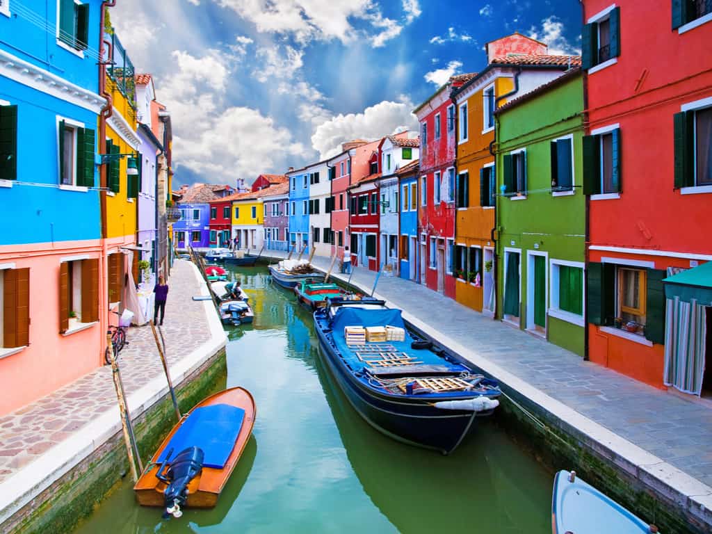 Colorful houses lining the canals in Burano, Italy, reflecting in the water and creating a vibrant scene