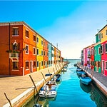 Boats moored along the brightly painted houses on Burano's canals, illustrating the island's fishing heritag