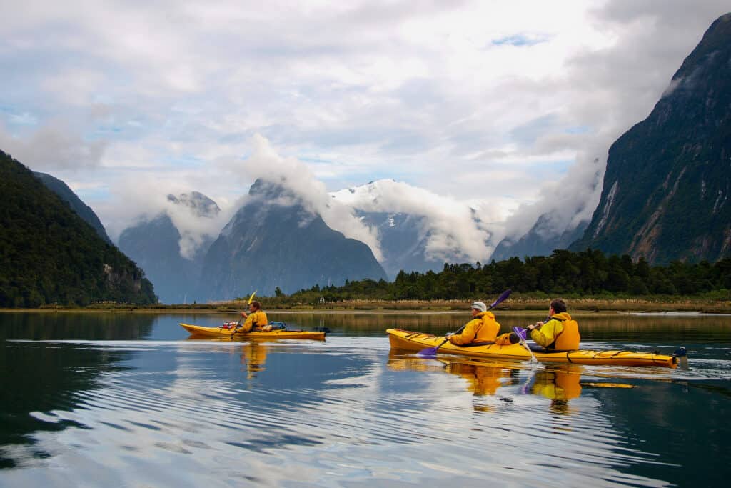 Kayakers exploring the calm waters of Milford Sound, surrounded by pristine nature.