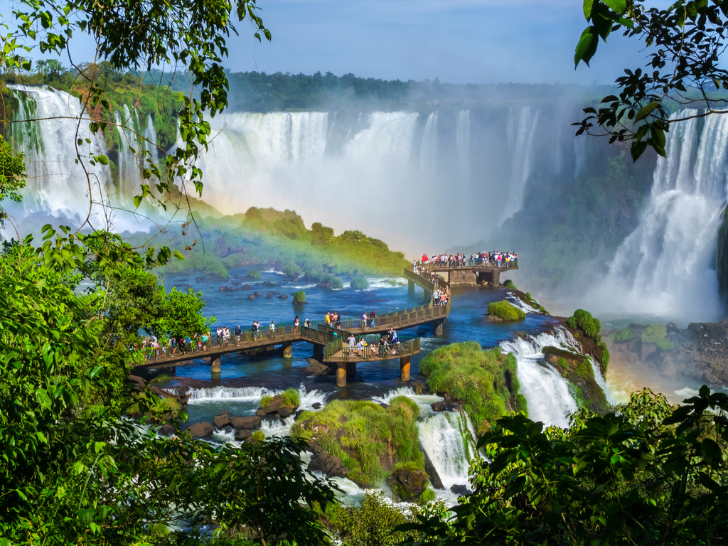 Rainbow forming over the misty waters of Iguazu Falls, adding a touch of magic to the scenic landscape
