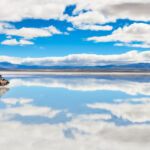 Expansive view of the Salar de Uyuni salt flats in Bolivia, showcasing the vast, white landscape under a clear blue sky