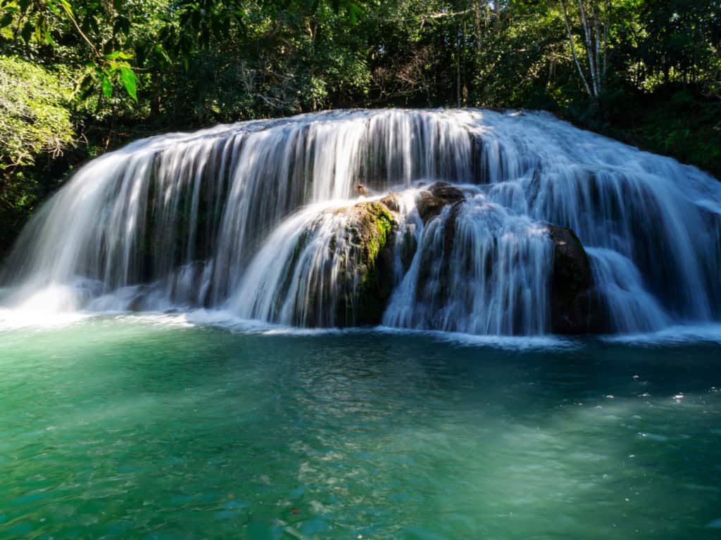 A scenic waterfall cascading into a clear pool in Bonito, inviting visitors for a refreshing swim.