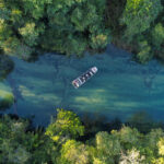 Tourists enjoying a tranquil boat ride on the serene waters of Bonito’s rivers, surrounded by untouched nature.