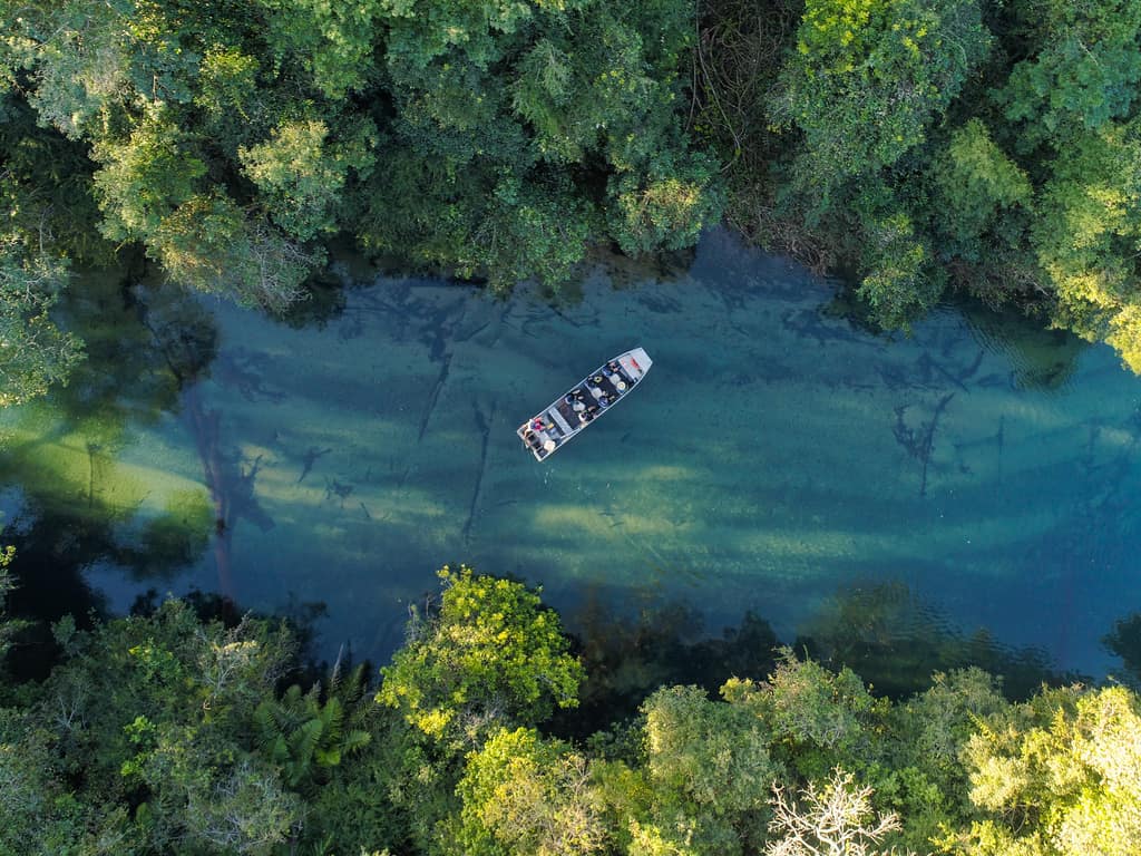 Tourists enjoying a tranquil boat ride on the serene waters of Bonito’s rivers, surrounded by untouched nature.