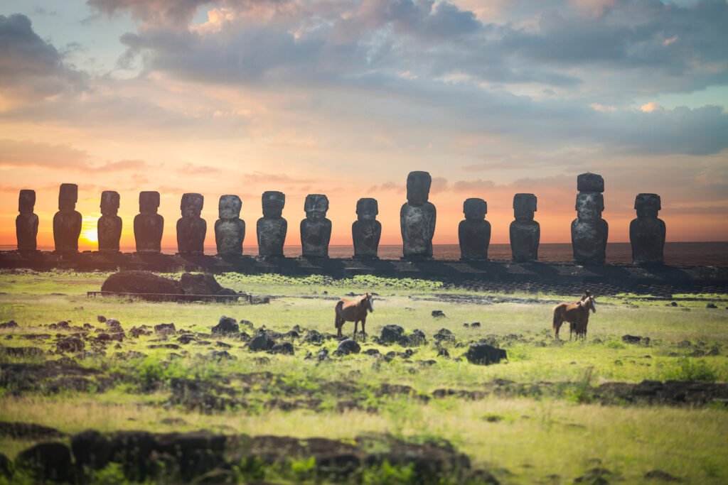 Sunset casting a golden glow over the moai statues at Ahu Tongariki on Easter Island, creating a mystical atmosphere